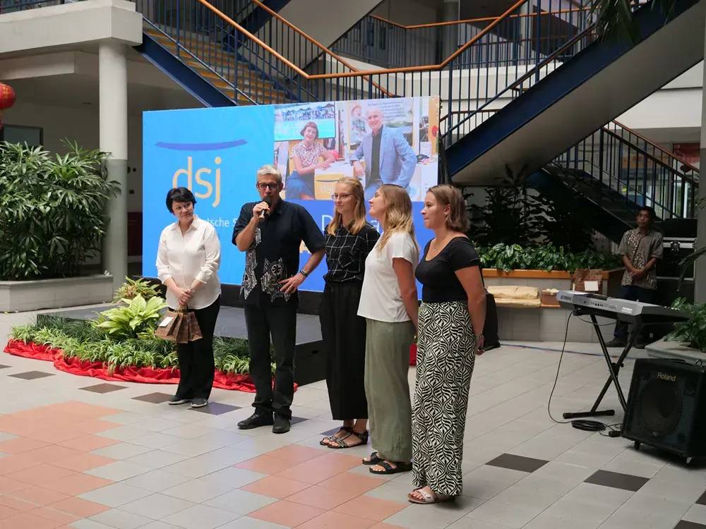 A group of people standing in front of a sign that says dsj