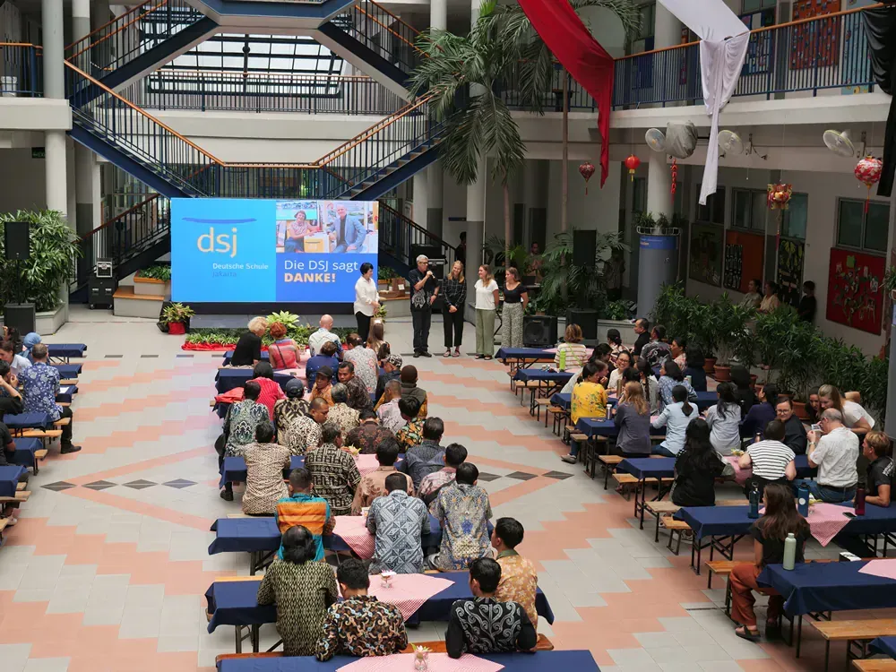 A large group of people are sitting at tables in a large room.