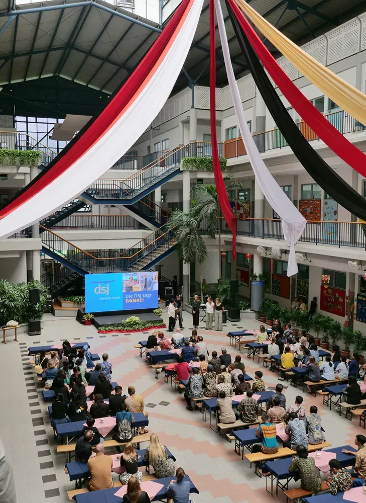 A large group of people are sitting at tables in a large building