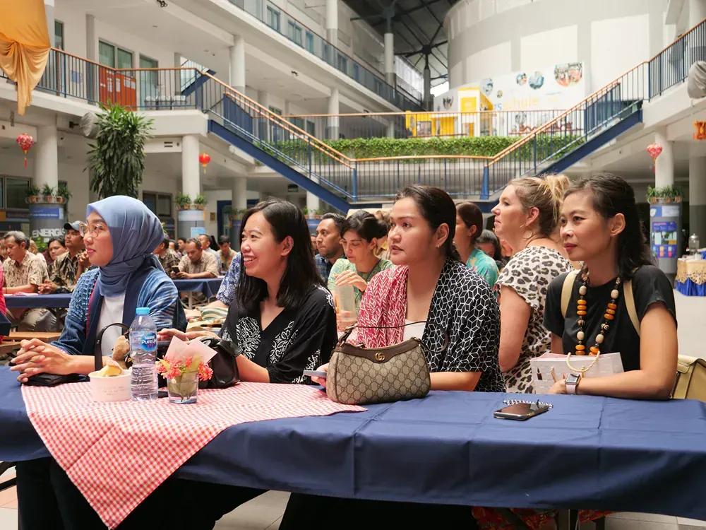 A group of women are sitting at tables in a large building.