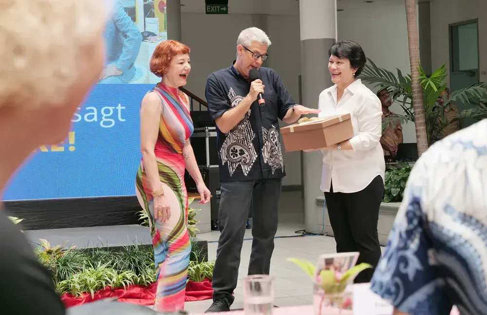 A man is holding a microphone while two women stand behind him