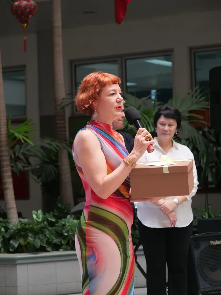 A woman speaking into a microphone while holding a box
