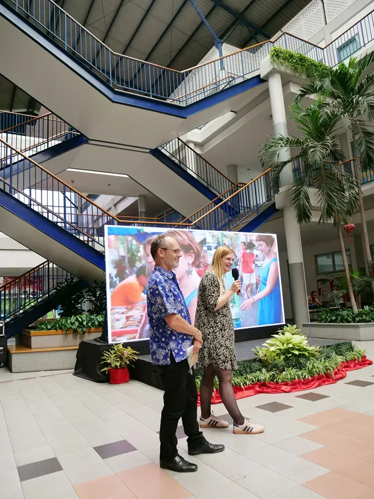A man and a woman standing in front of a large screen