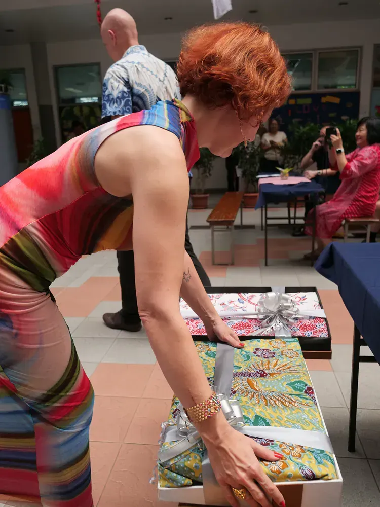 A woman in a colorful dress is putting a gift on a table.