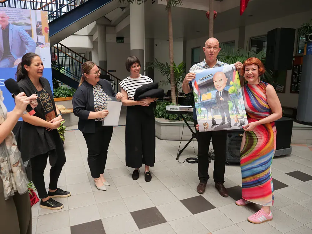 A group of people standing around a man holding a painting