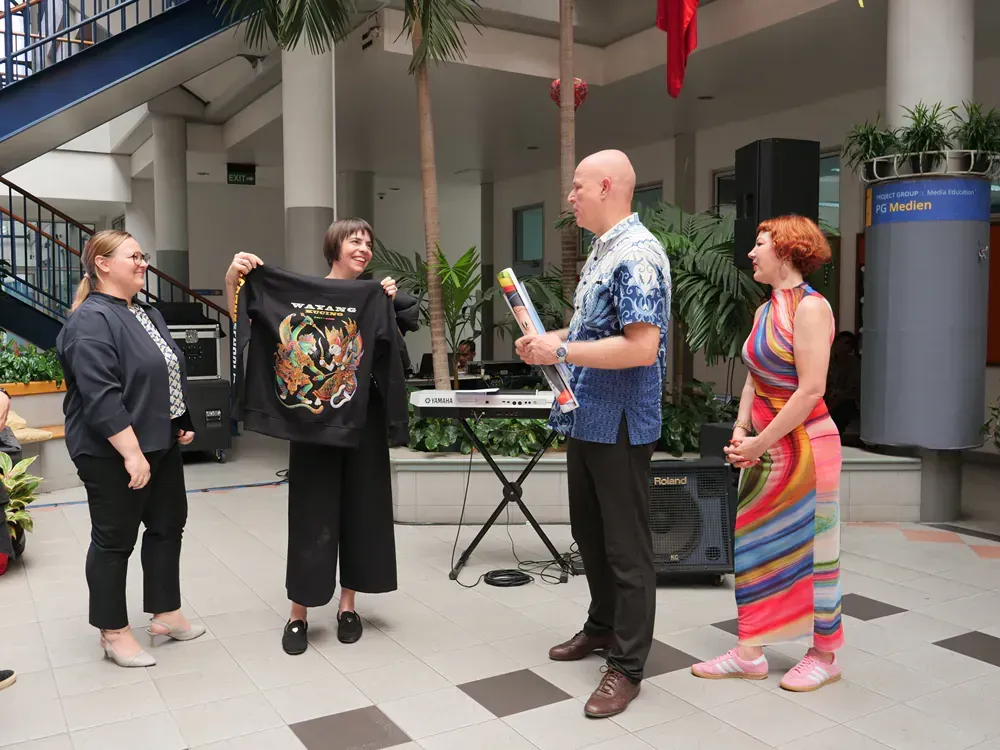 A group of people are standing around a man holding a shirt with a tiger on it.