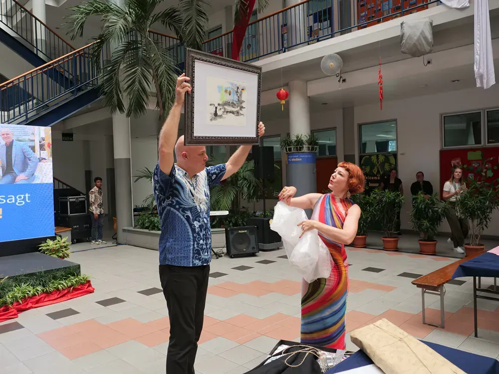 A man is holding a framed picture over his head while a woman looks on.