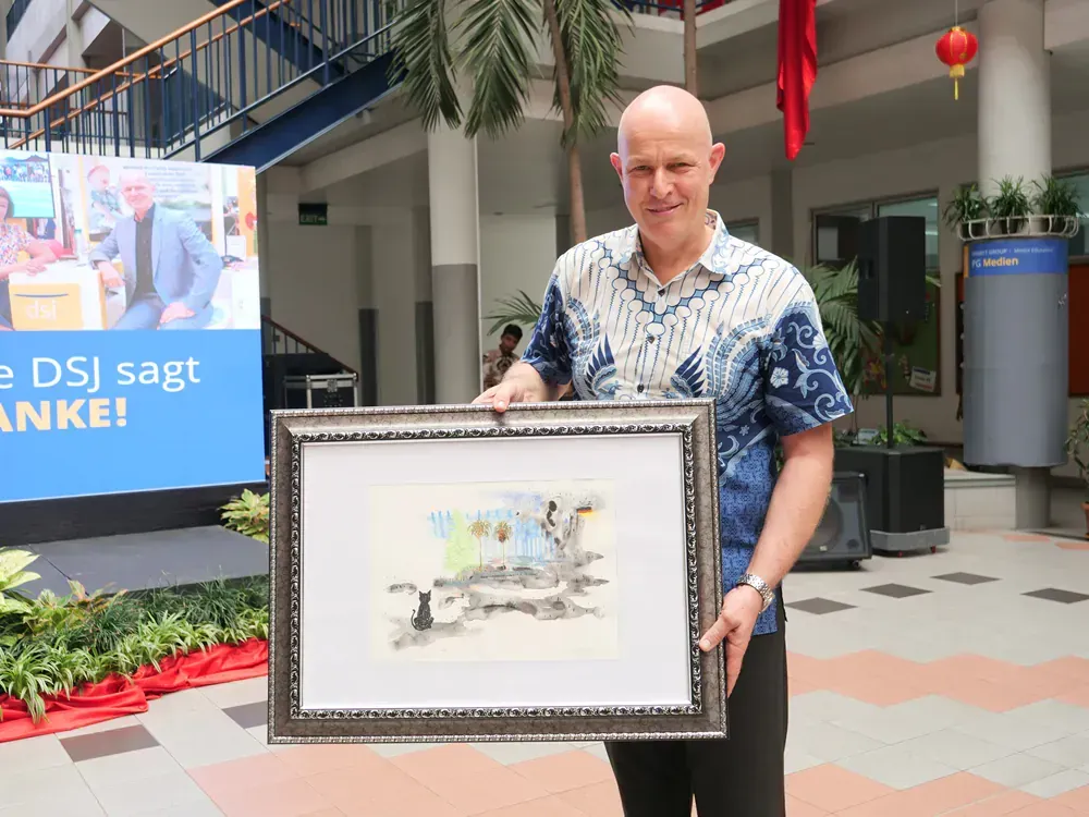 A man in a blue shirt is holding a framed picture