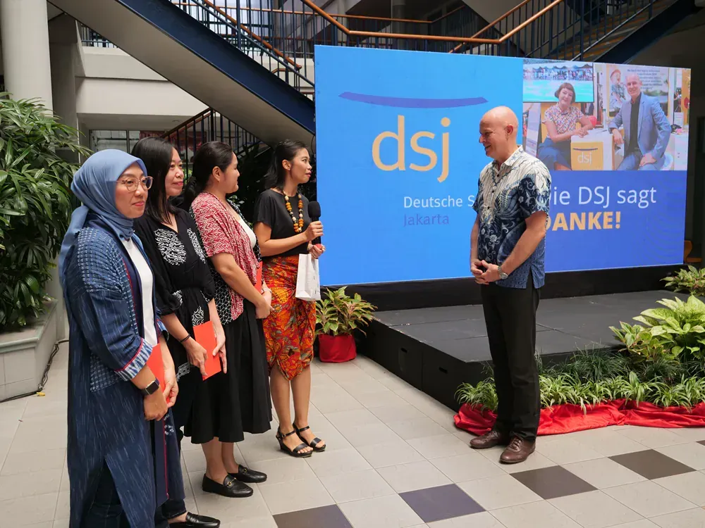 A group of people standing in front of a sign that says dsj