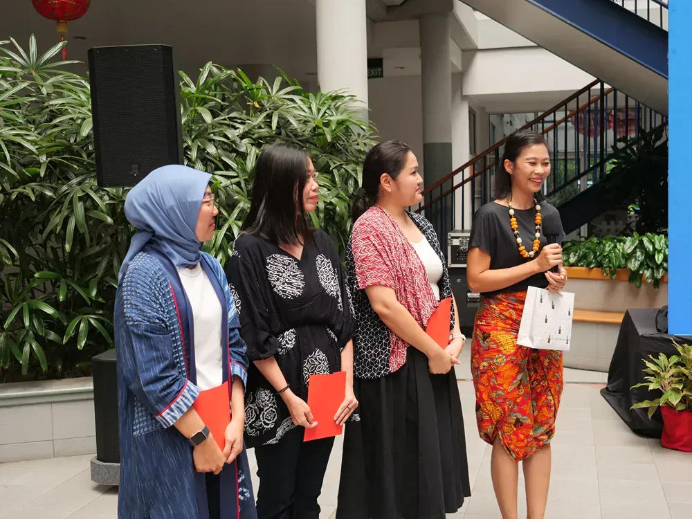 A group of women standing next to each other holding papers and a microphone.
