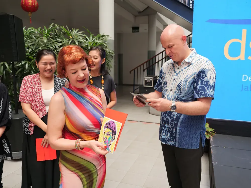 A group of people are standing around a woman holding a book