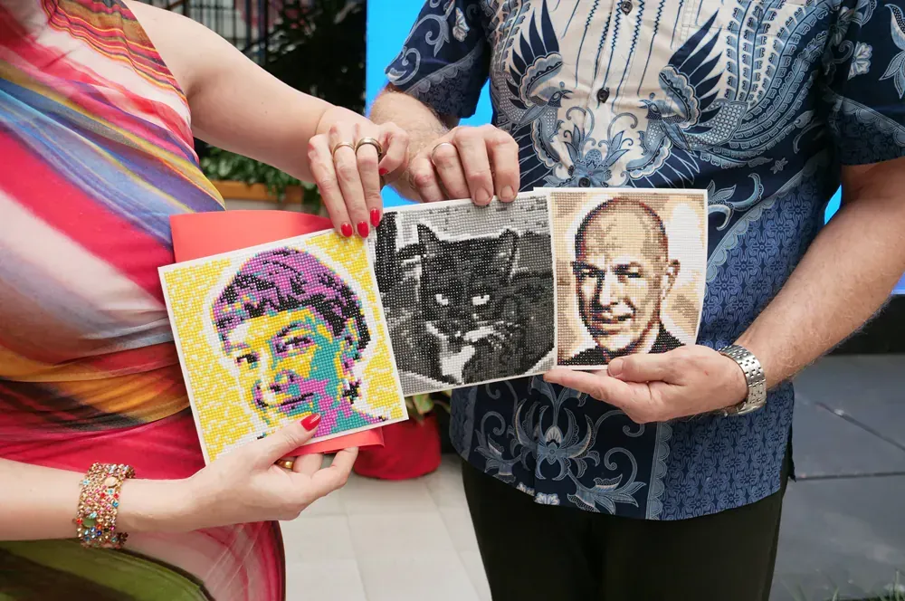 A man and a woman are holding pictures of a cat and a man.