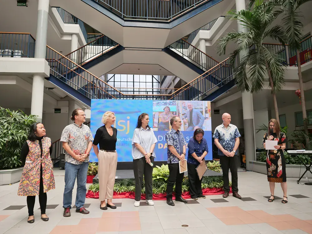 A group of people are standing in front of a large screen in a building.
