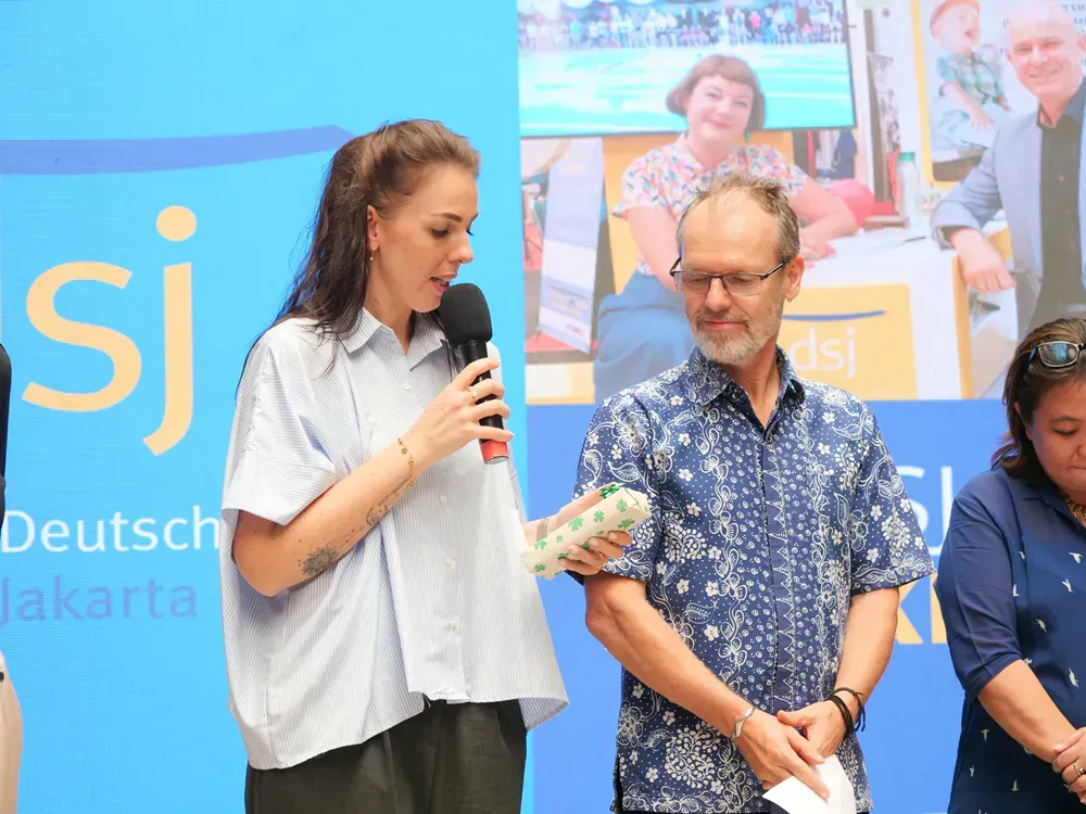 A woman is holding a microphone while standing next to a man and a woman.