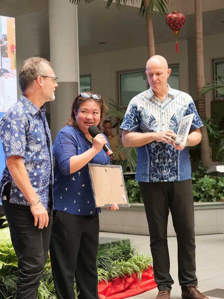 A woman is holding a microphone while standing next to two men.