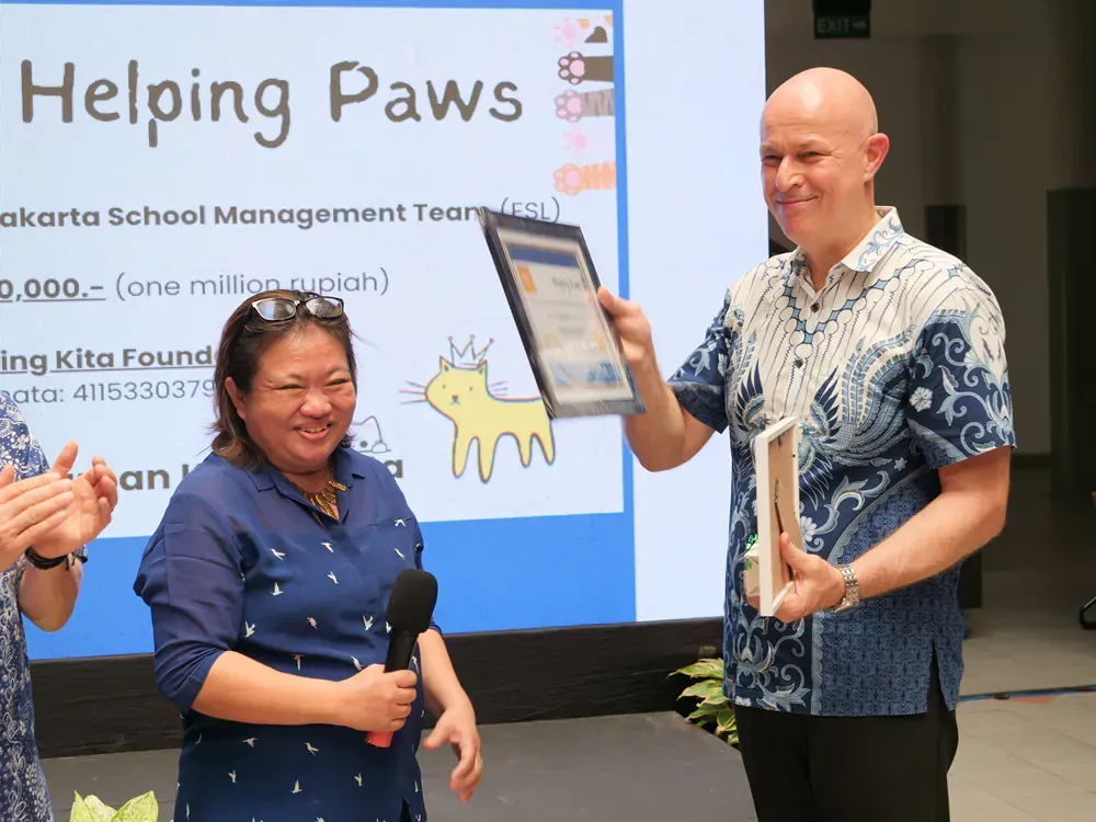 A man and woman are standing in front of a screen that says helping paws