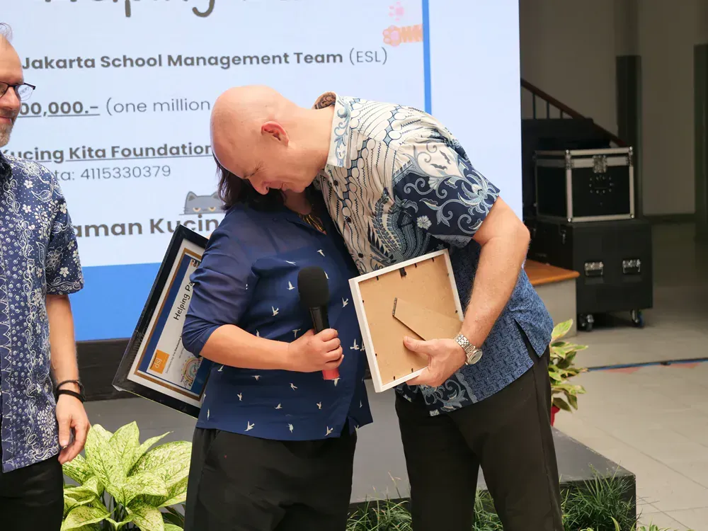A man is hugging a woman who is holding a framed picture.