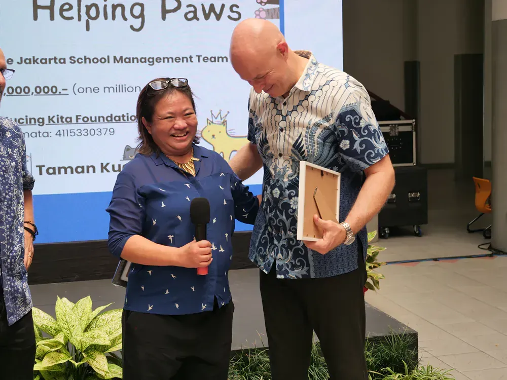 A man and a woman are standing in front of a sign that says helping paws