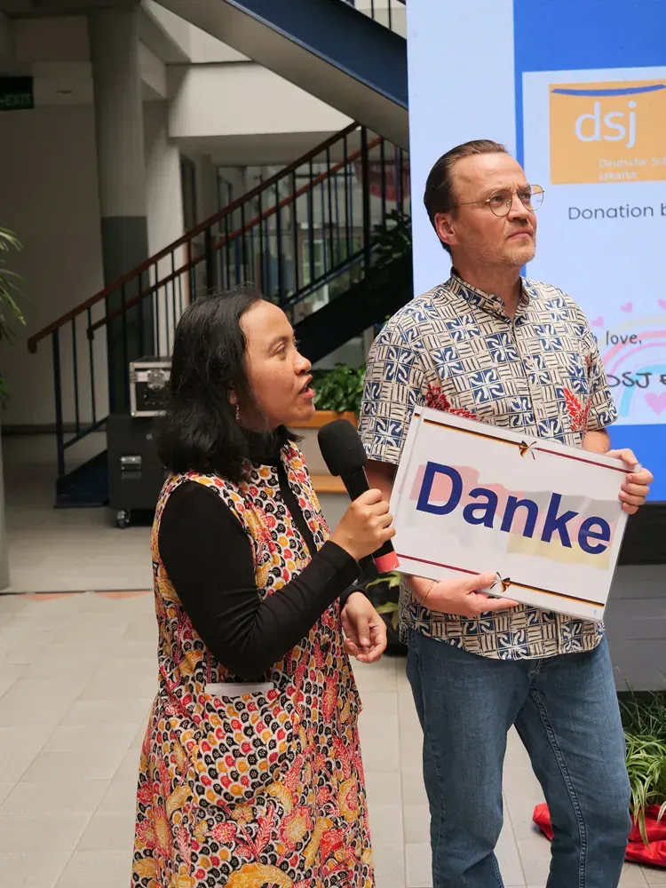 A man and a woman are holding a sign that says danke.