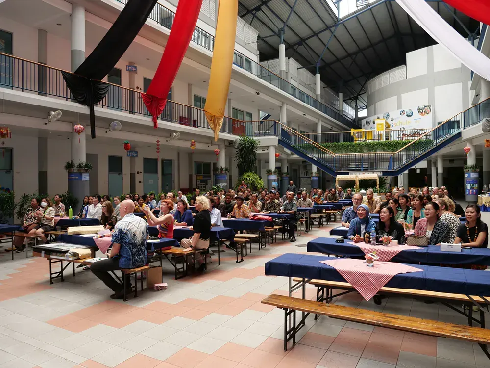 A large group of people are sitting at tables in a large building.