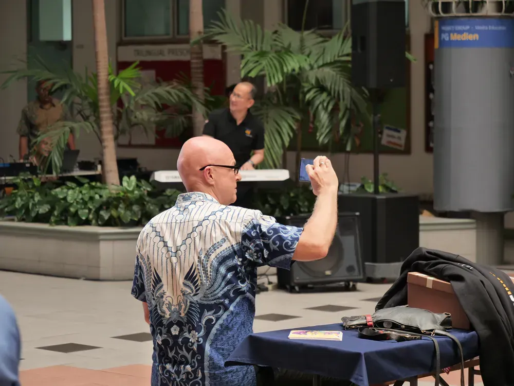A bald man in a blue shirt is taking a picture