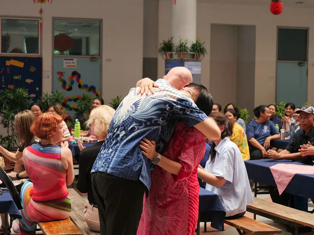 A man and woman are hugging each other in front of a crowd of people.