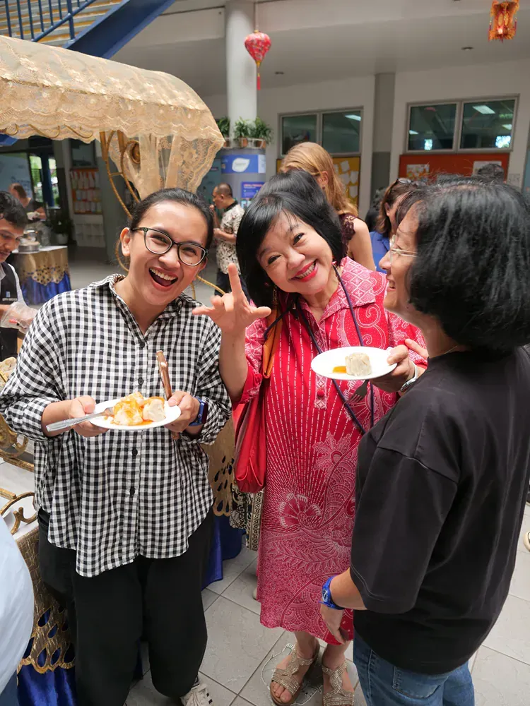 Three women are standing next to each other holding plates of food.