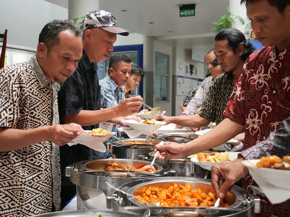 A group of men are eating food from a buffet line.