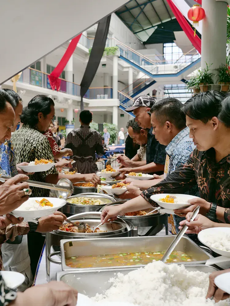 A group of people are eating food from a buffet line.