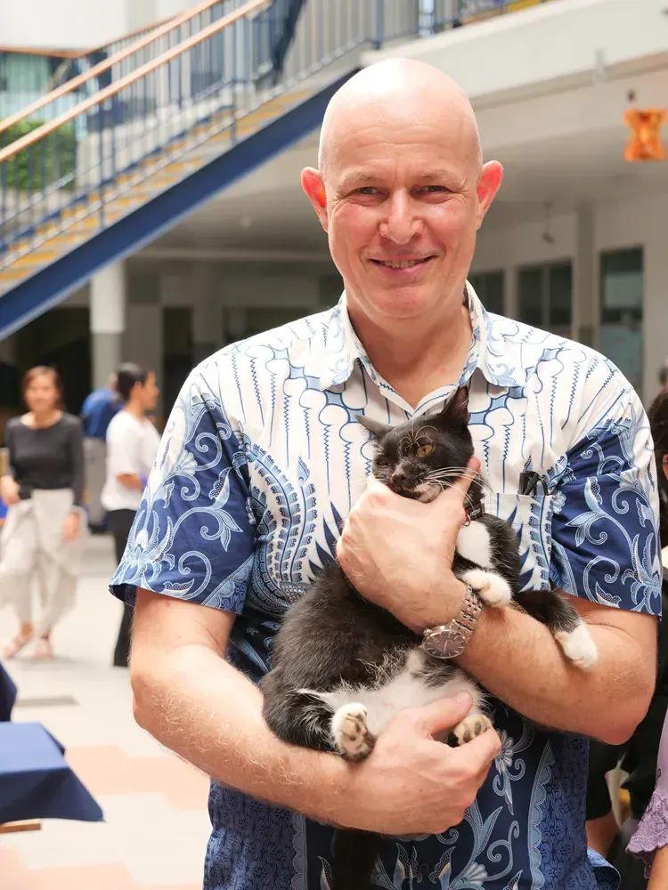 A man in a blue and white shirt is holding a cat