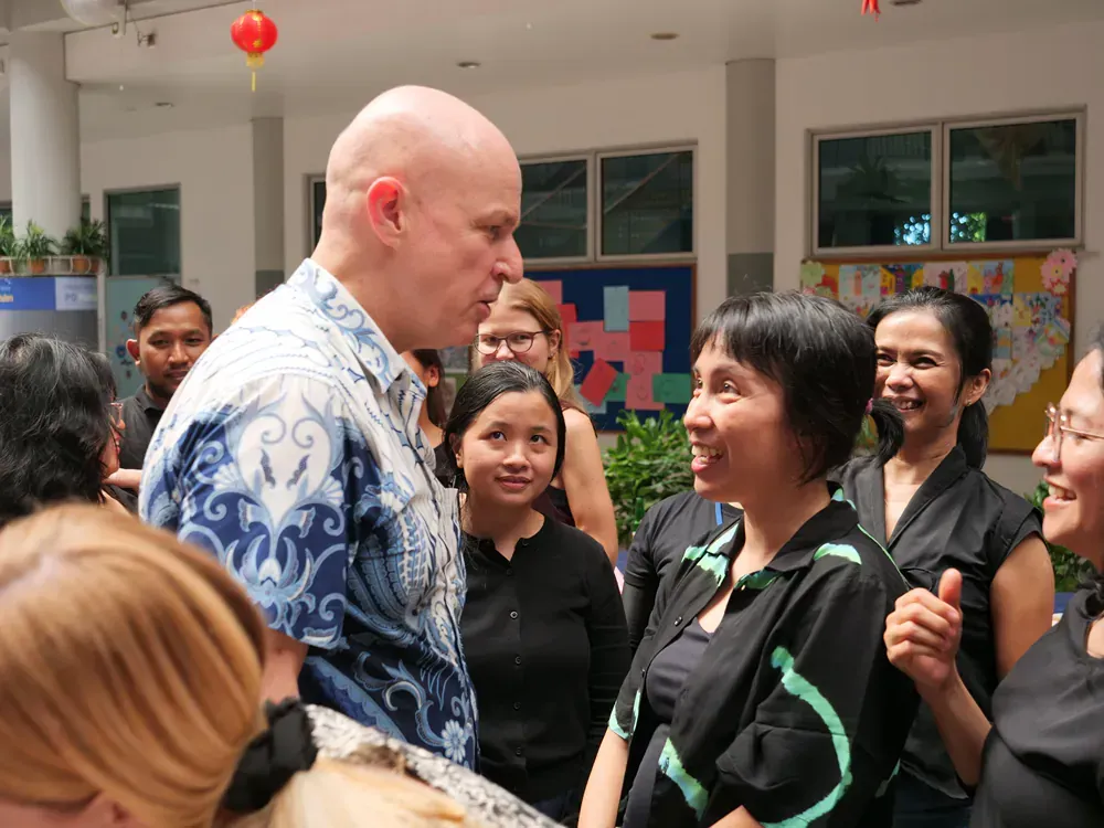 A bald man is talking to a group of women