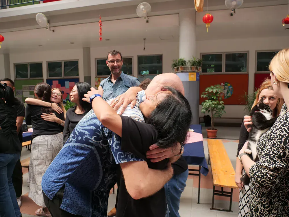 A group of people are hugging each other in a room.