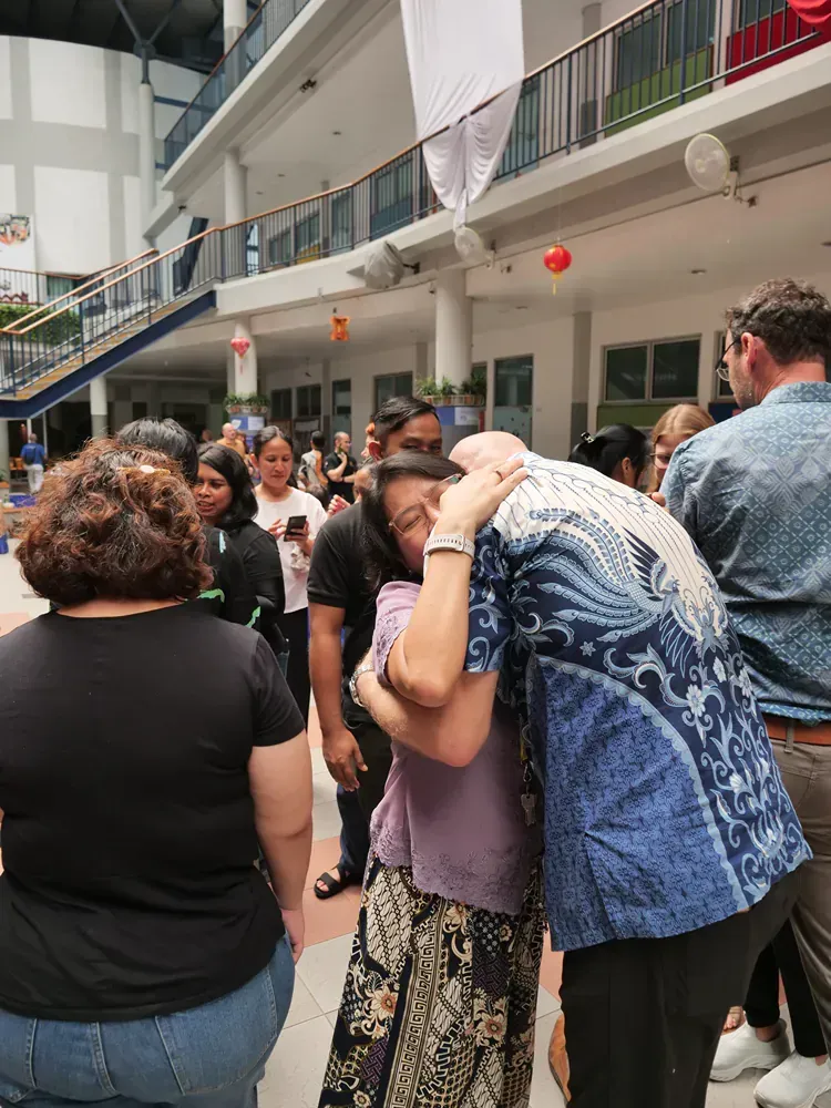 A man in a blue shirt is hugging a woman in a crowd of people.