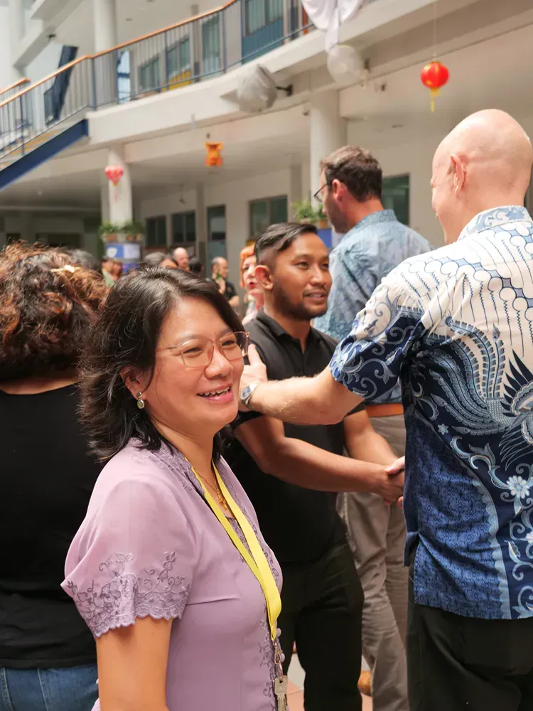 A woman in a purple shirt is standing in a crowd talking to a man in a blue shirt.