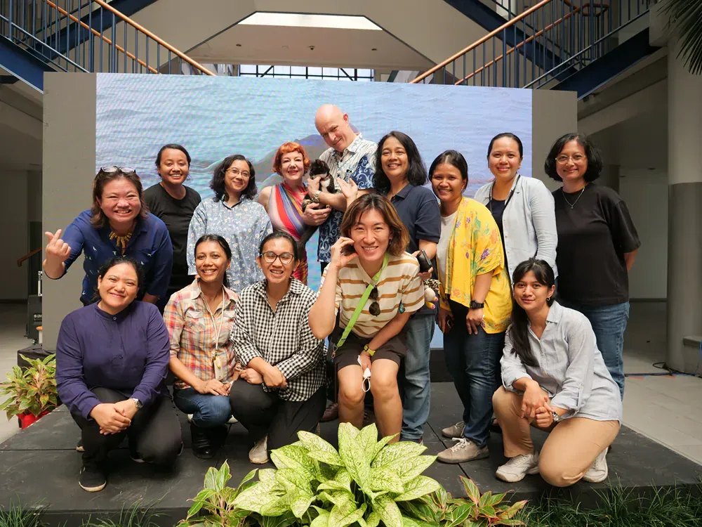 A group of people are posing for a picture in front of a large screen.