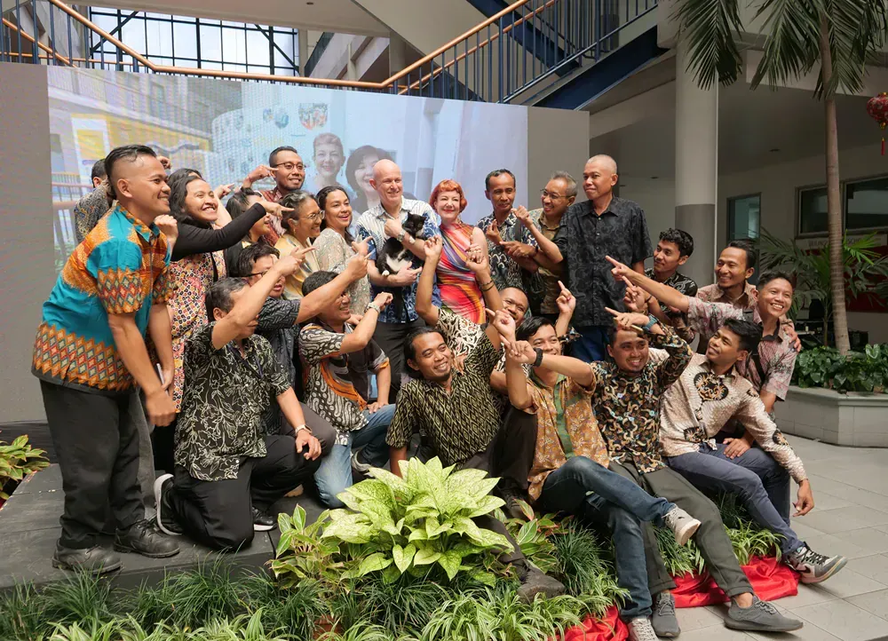 A group of people are posing for a picture in front of a large screen.
