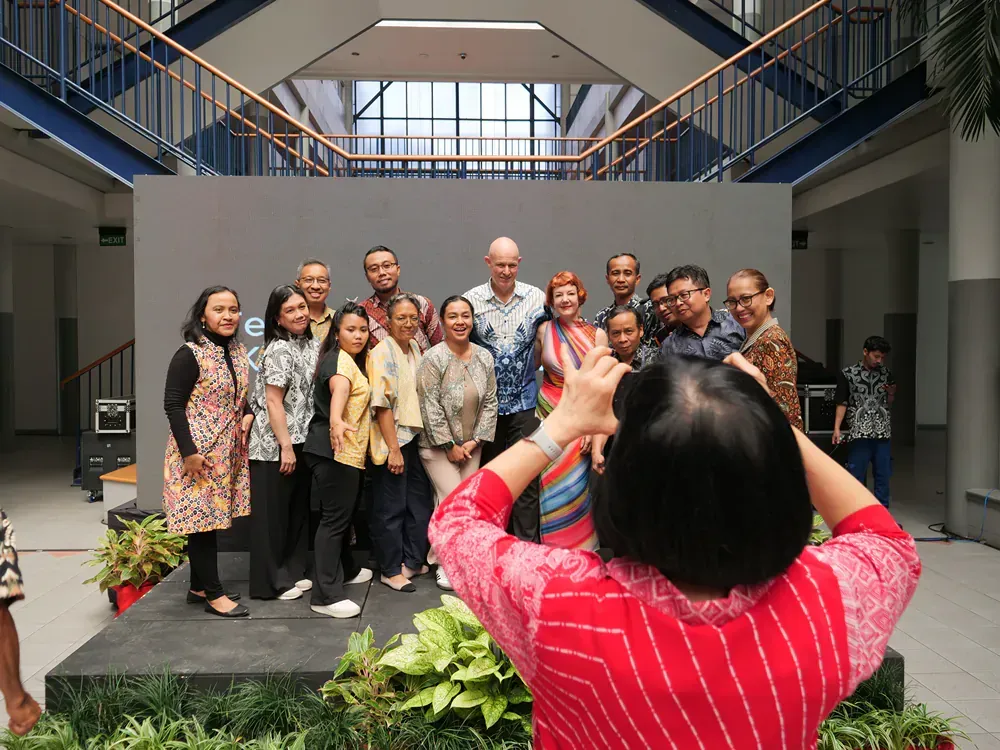 A woman is taking a picture of a group of people in a building.