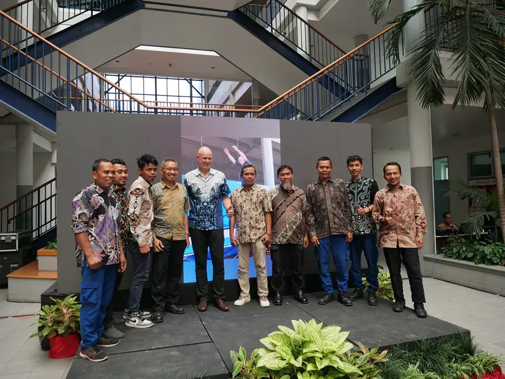 A group of men are posing for a picture in front of a large screen.
