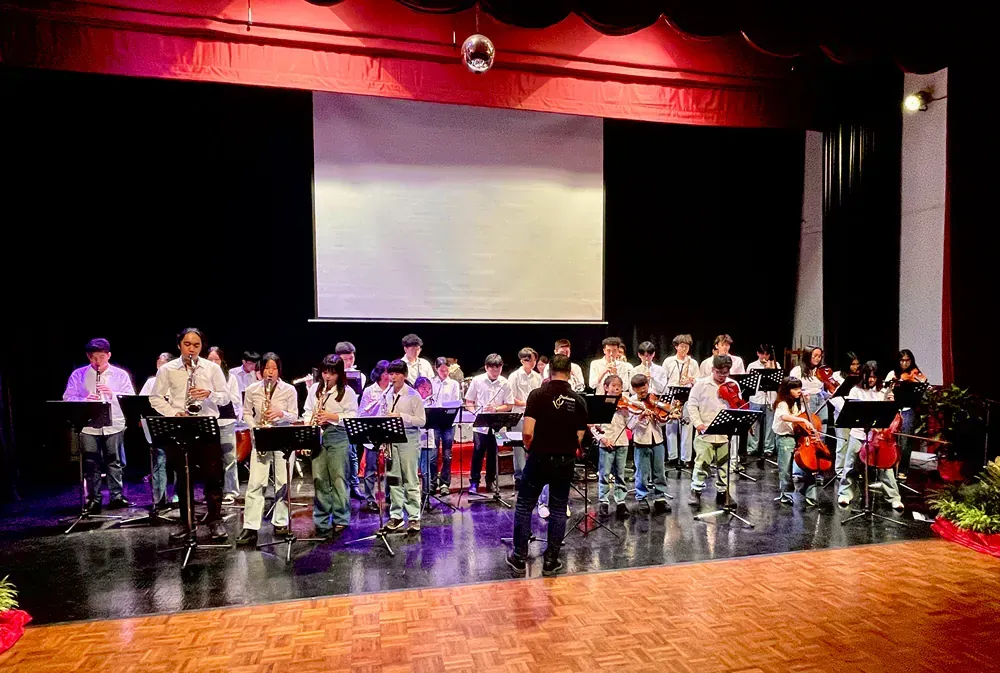 A large band is playing on a stage in front of a large screen.