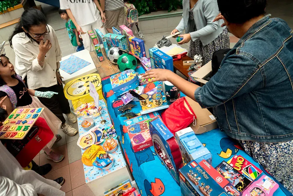 A group of people are standing around a table full of toys.