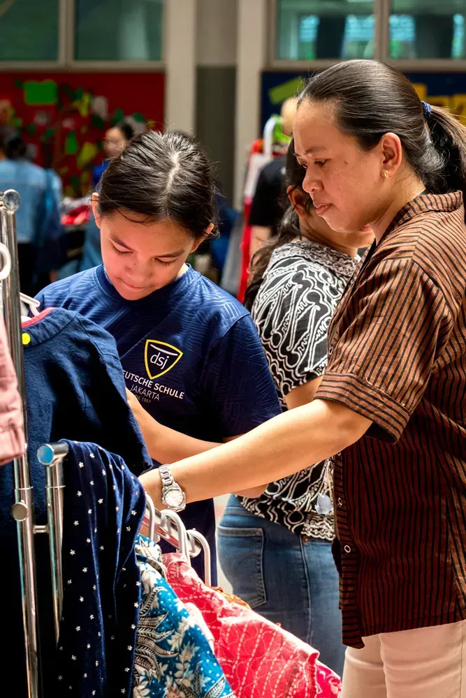 A woman and a girl are looking at clothes in a store.