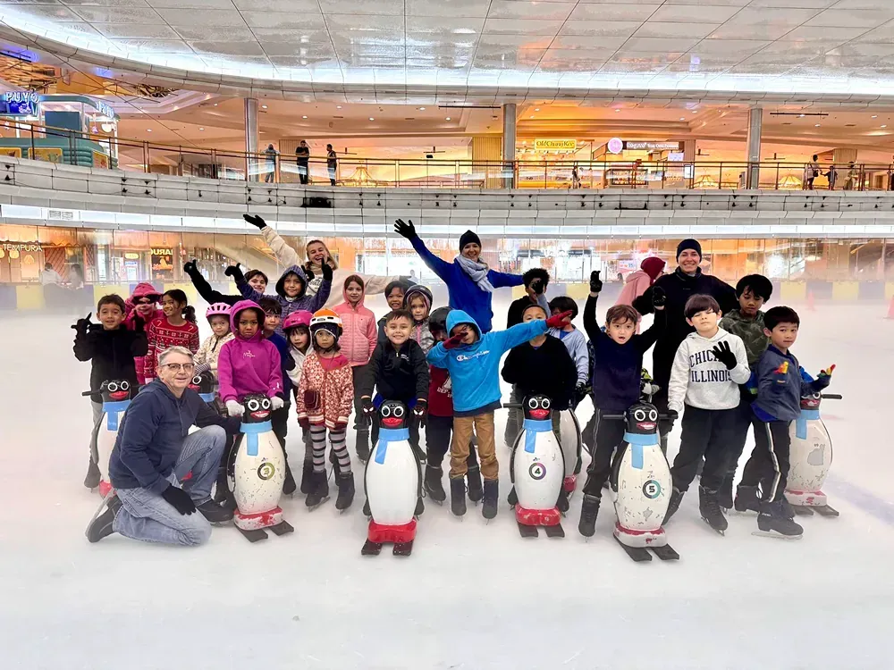 A group of children are posing for a picture on an ice rink.