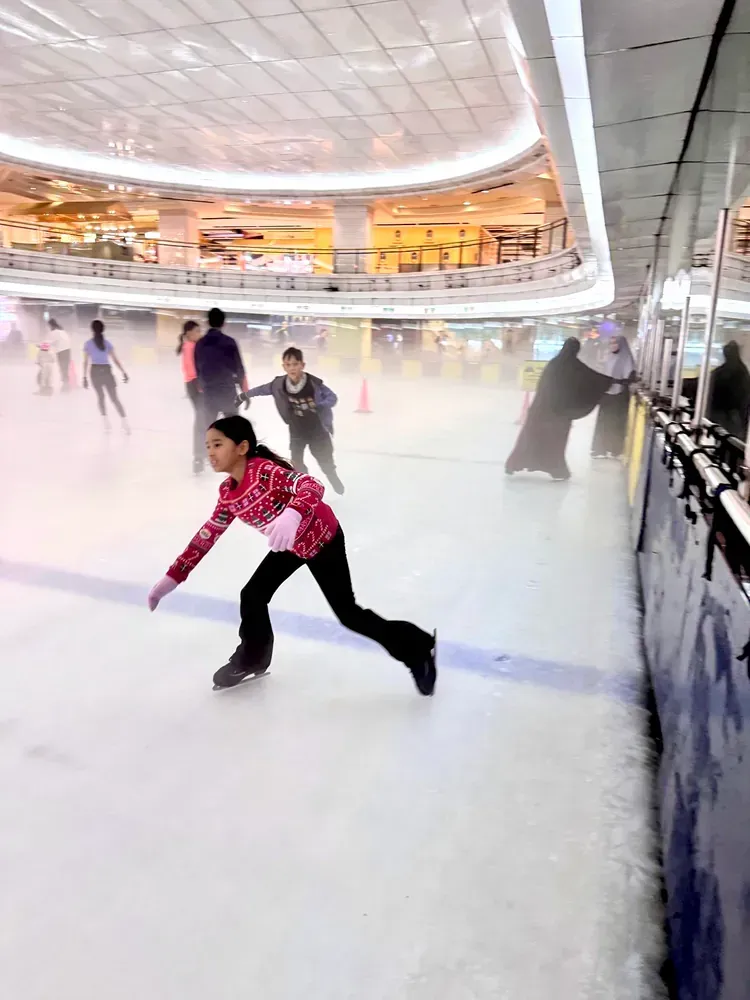 A young girl is ice skating on a rink in a mall.
