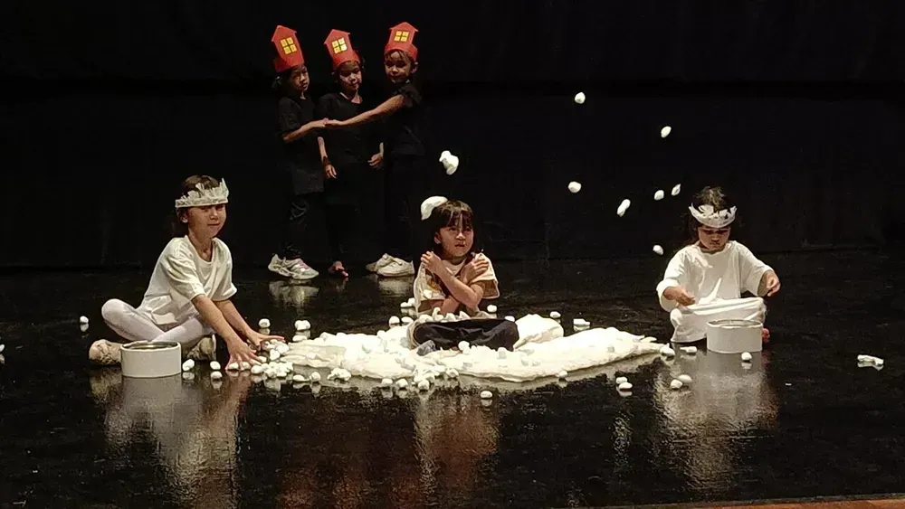 A group of children are playing with snow on a stage.