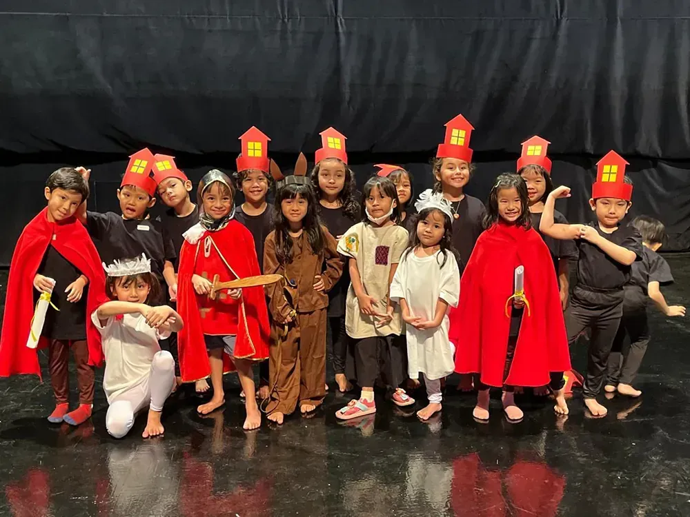 A group of children dressed in costumes are posing for a picture on a stage.