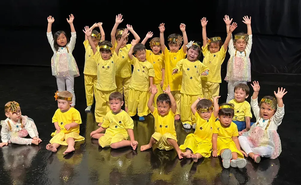 A group of children are posing for a picture on a stage.