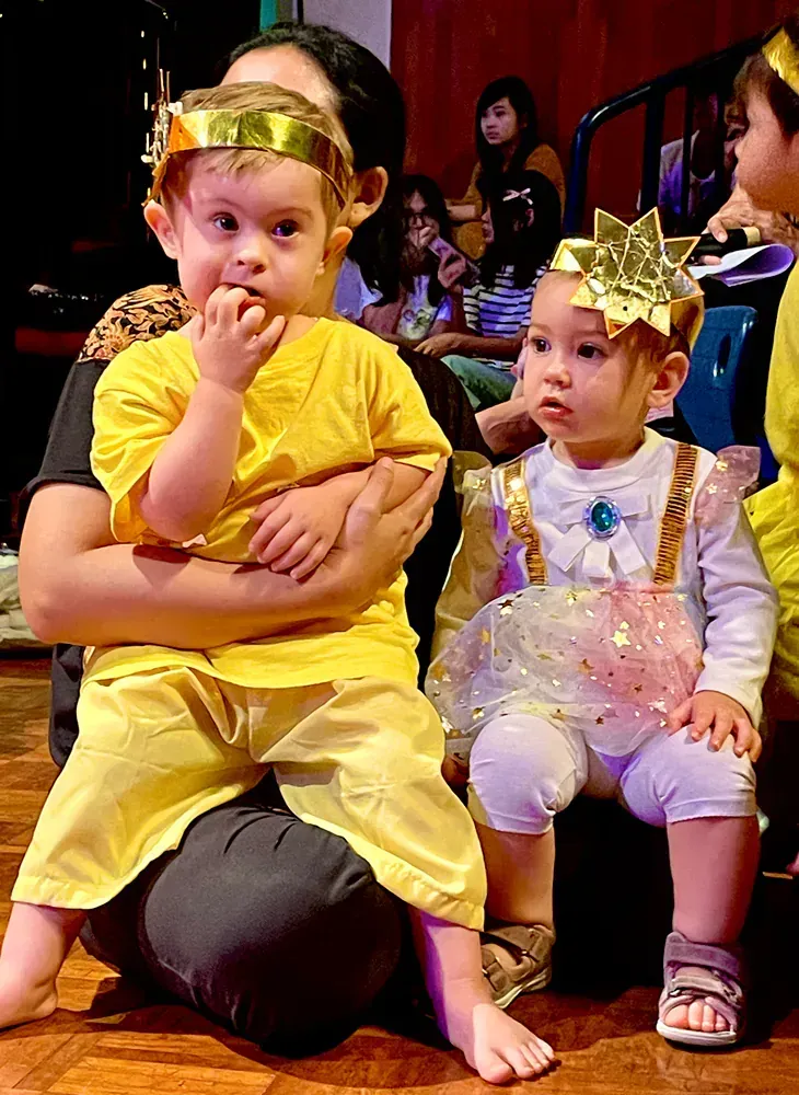 A woman is holding two babies dressed in costumes.