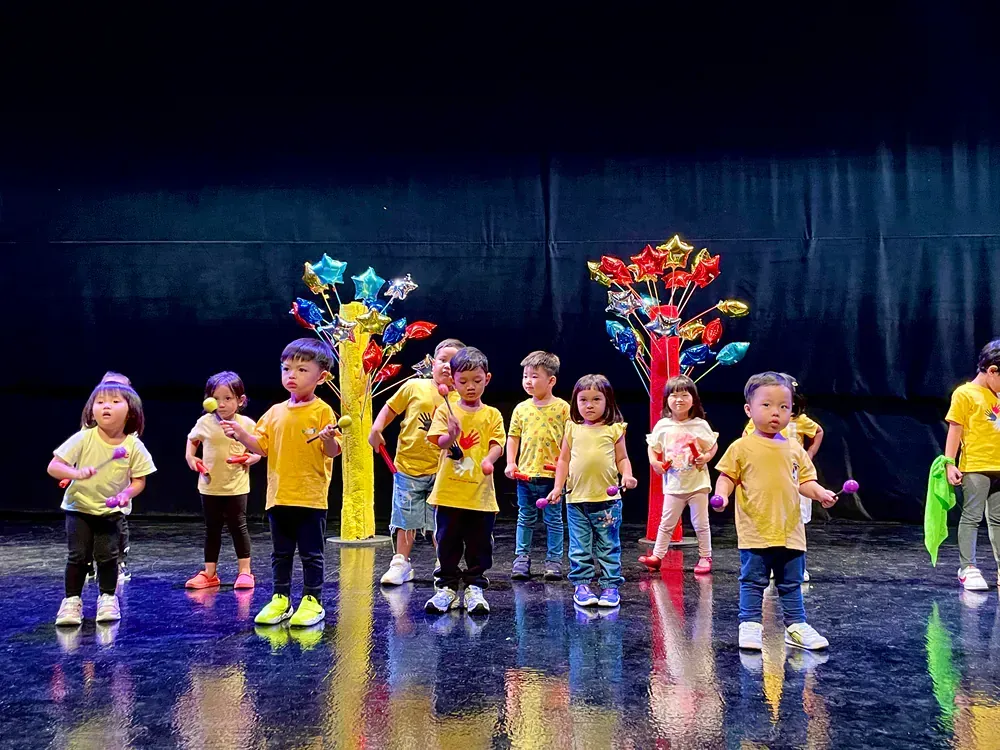 A group of children are standing on a stage holding instruments.