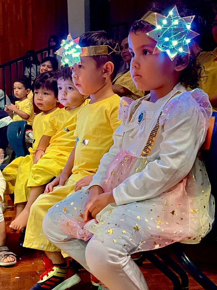 A group of children are sitting in a row wearing costumes.