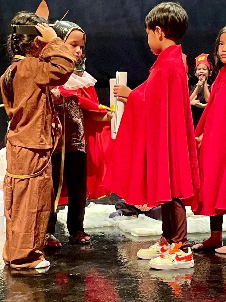 A group of children dressed in native american costumes are standing on a stage.